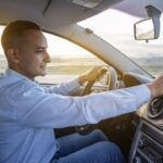 driver is checking something on his mobile phone on the dashboard