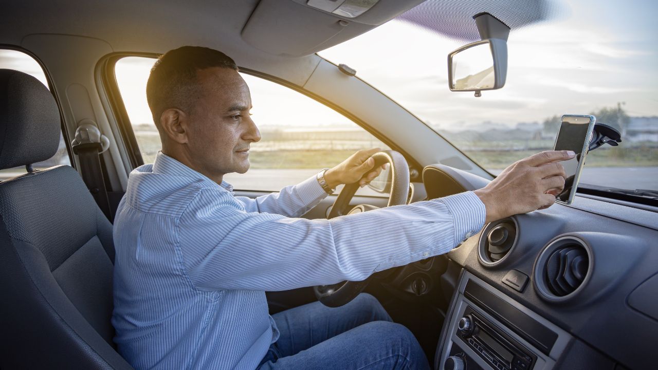 driver is checking something on his mobile phone on the dashboard